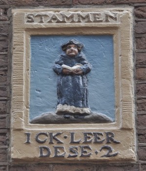 The First Estate: a clergyman educates the two others (17th-century gable stone; Amsterdam)